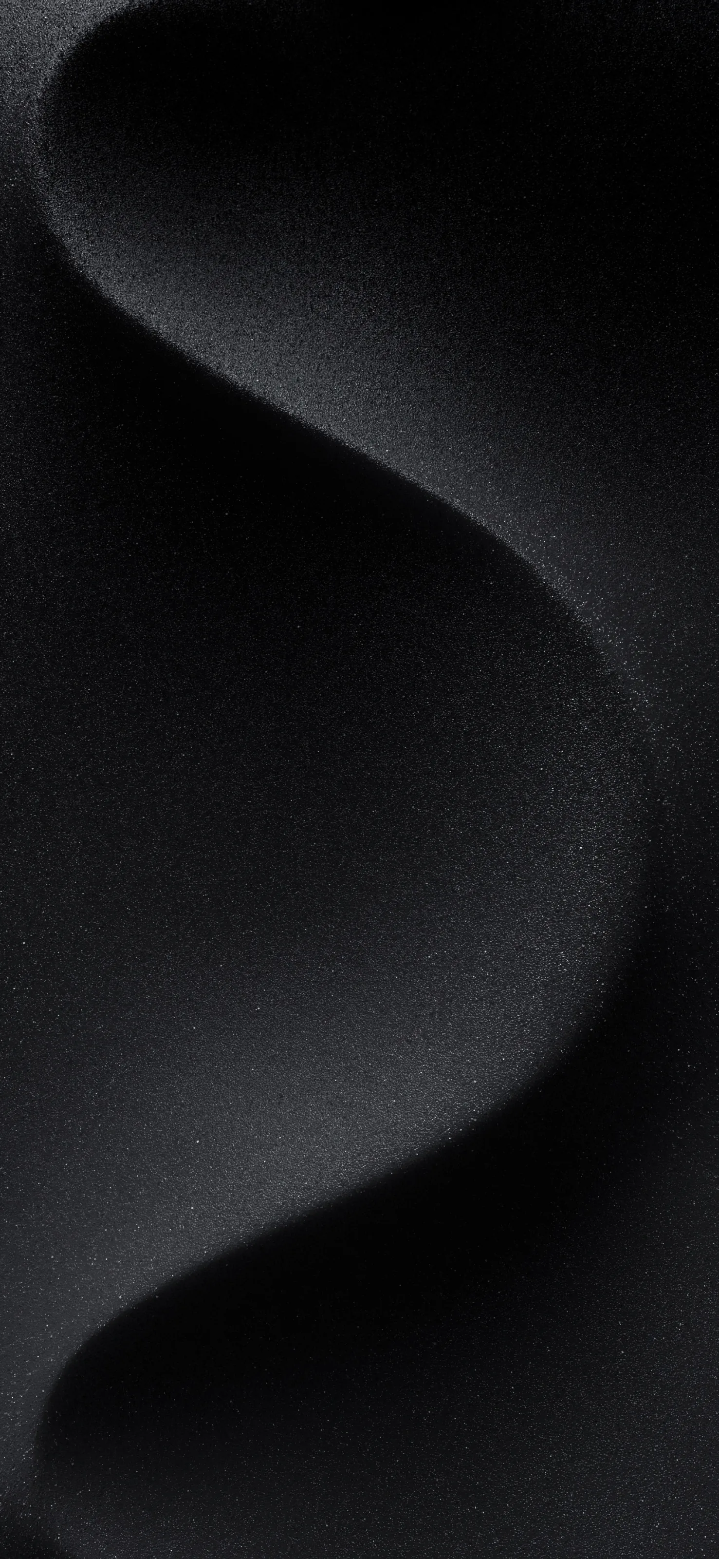 A single soft fold runs down a matte black surface, the grain of the weave showing only where the light grazes the crest.