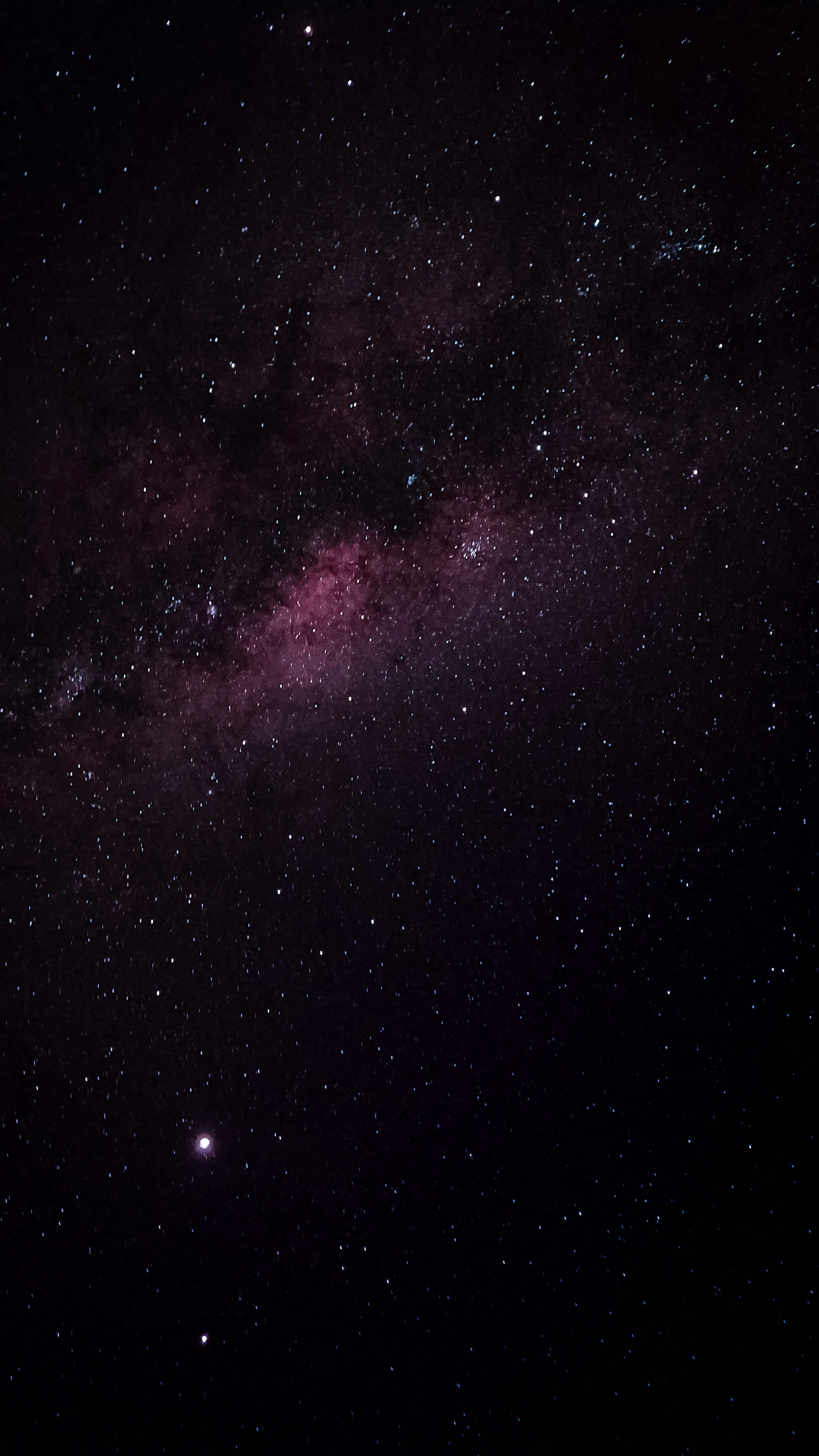 The Milky Way's core glows dusty pink in the upper half, one bright star burning lower left — the bottom third stays near-black for app icons.