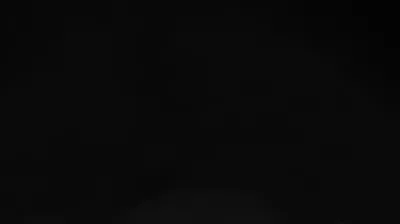 Deep black across the whole frame with one pale bloom pushing up from the bottom centre, so desktop icons sit clear of it.