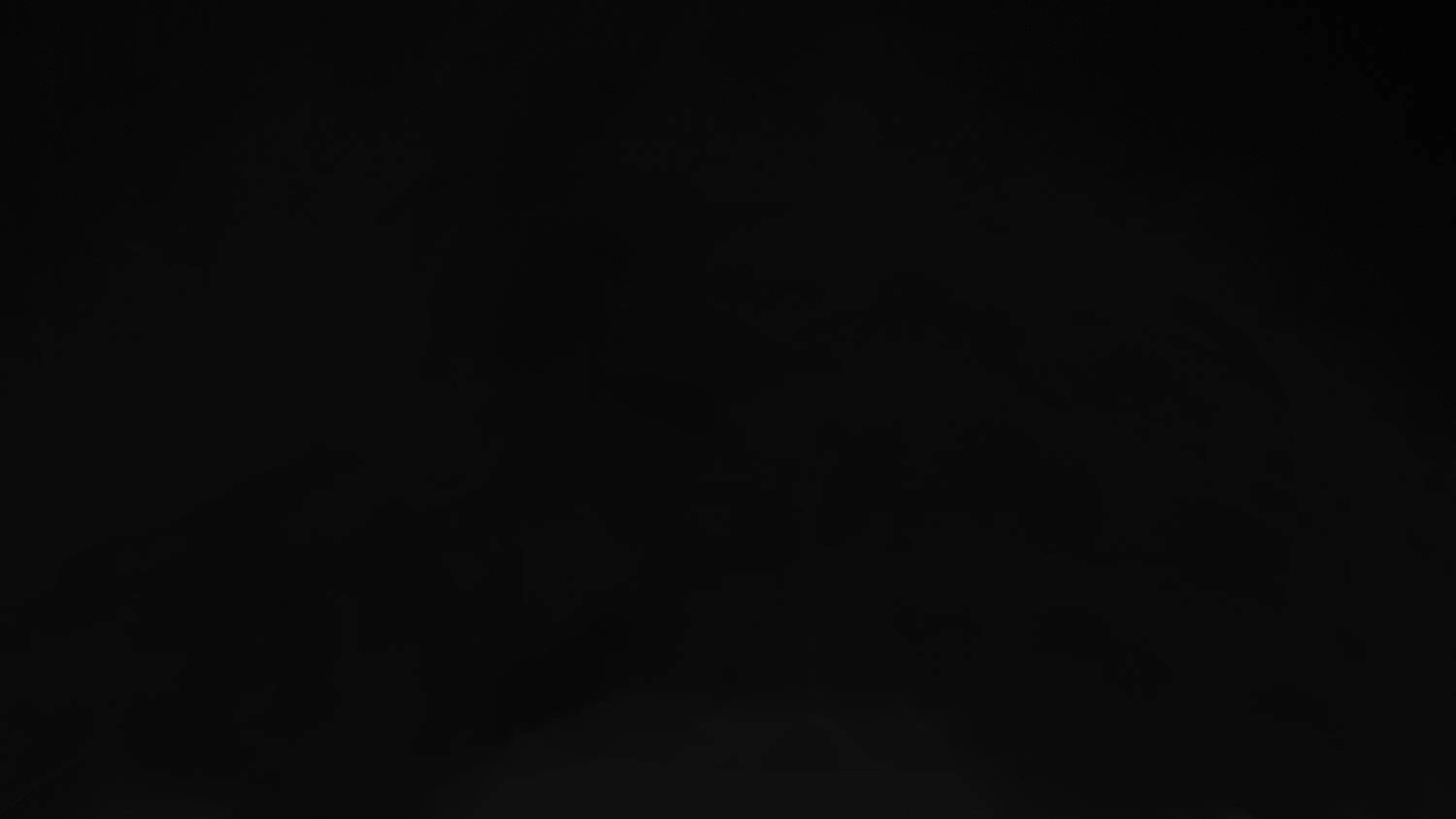 Deep black across the whole frame with one pale bloom pushing up from the bottom centre, so desktop icons sit clear of it.