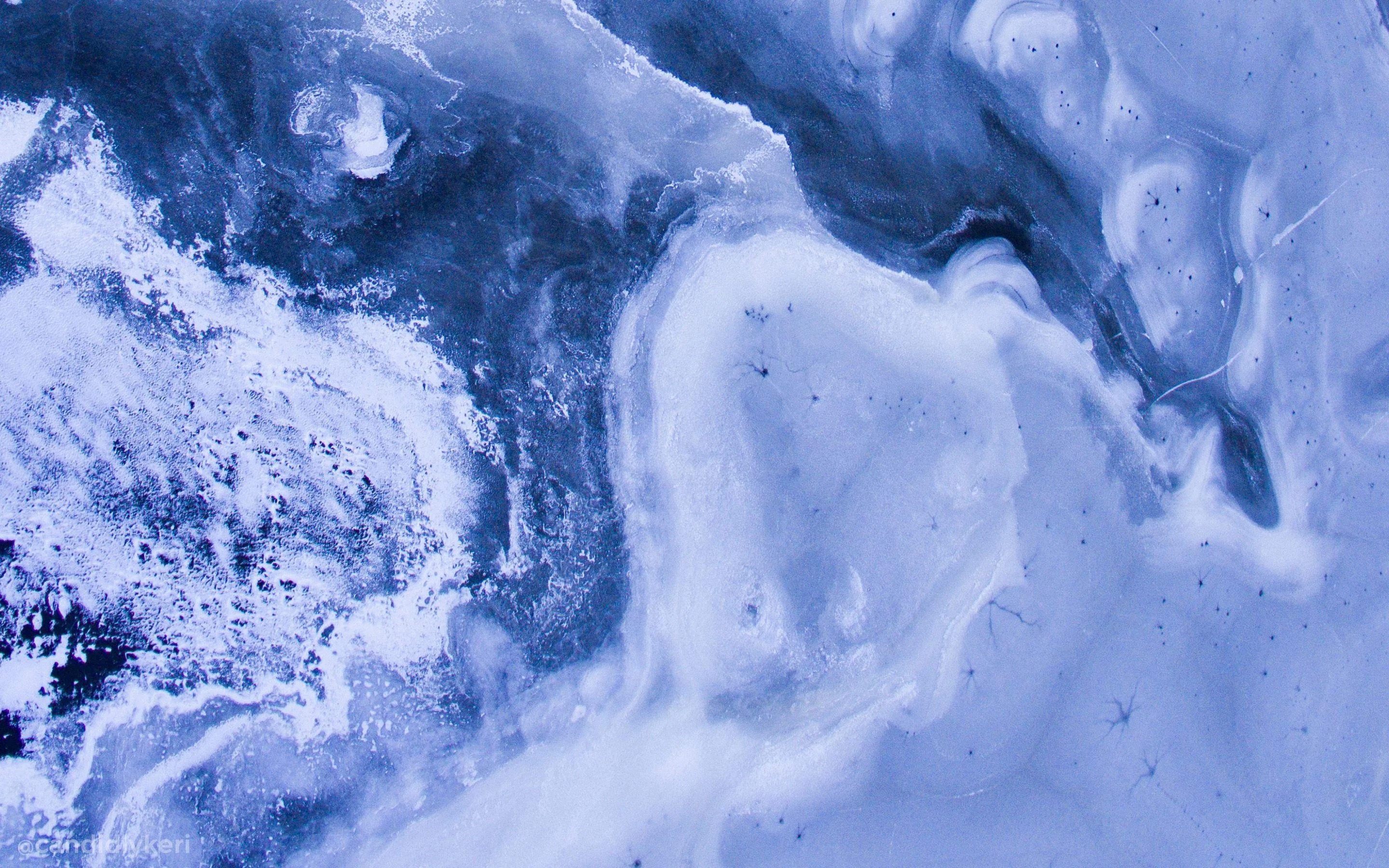 Pale slate and periwinkle pigment folds across the frame like an aerial ice floe, a darker teal channel cutting through the upper right corner.