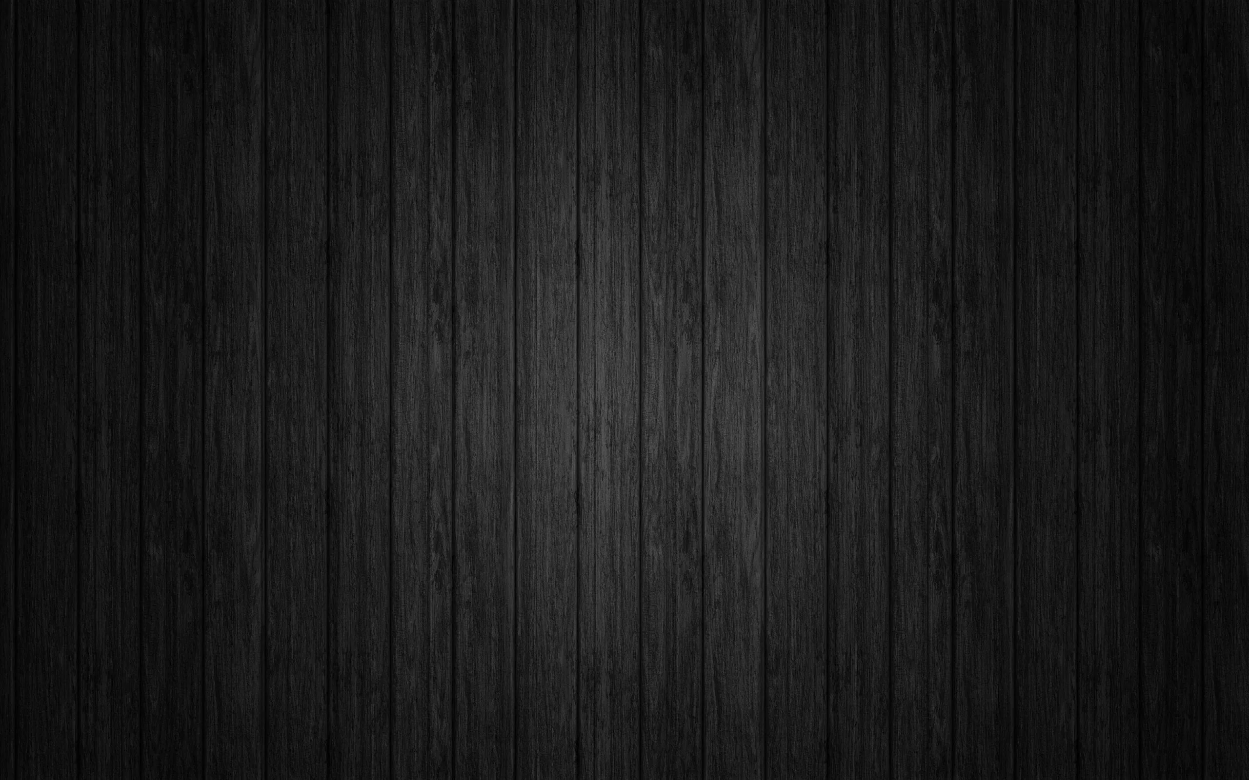 Vertical wooden boards run the full height, grain showing faintly in the lit middle band while the top and bottom drop into black.