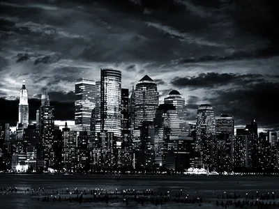 Lit office towers crowd the waterfront while a bank of dark cloud presses down from above, the whole scene cooled to charcoal.
