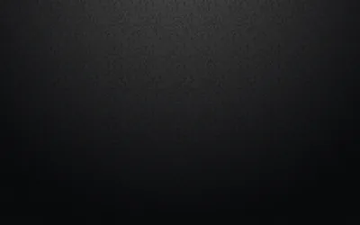 A finely grained dark surface lit from above so the top third lifts to grey, the bottom corners falling into black.