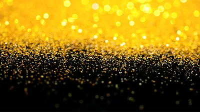 Bright gold sparkle at the top dissolves into a field of black glitter below, leaving the dark lower half clear for a phone dock or desktop icons.