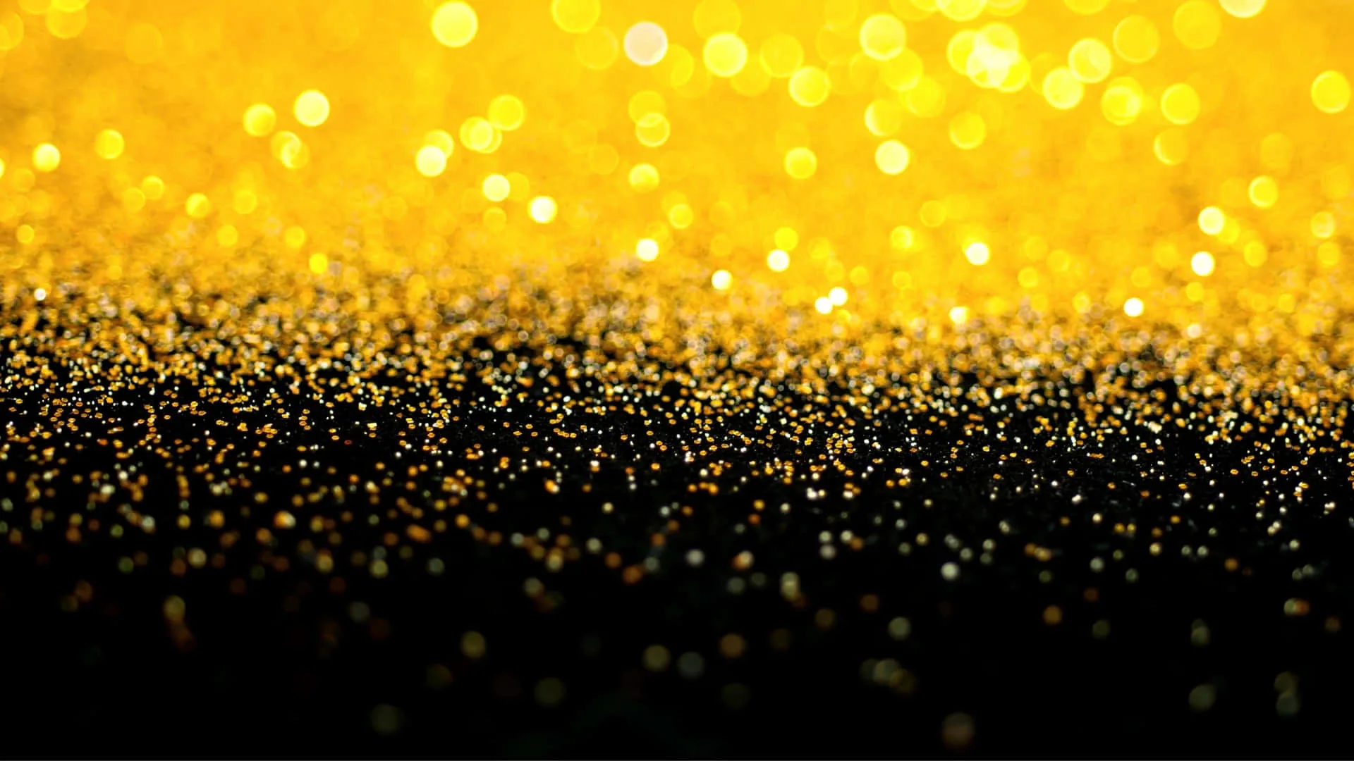 Bright gold sparkle at the top dissolves into a field of black glitter below, leaving the dark lower half clear for a phone dock or desktop icons.