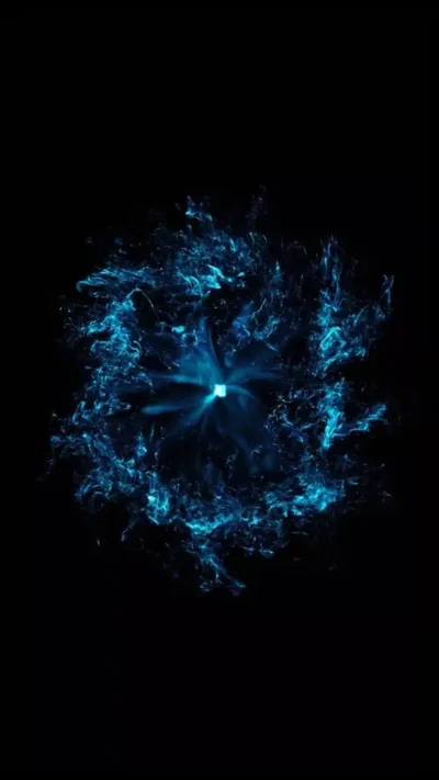 A burst of water and light scatters outward from a small bright core, the droplets breaking into fine spray against solid black.