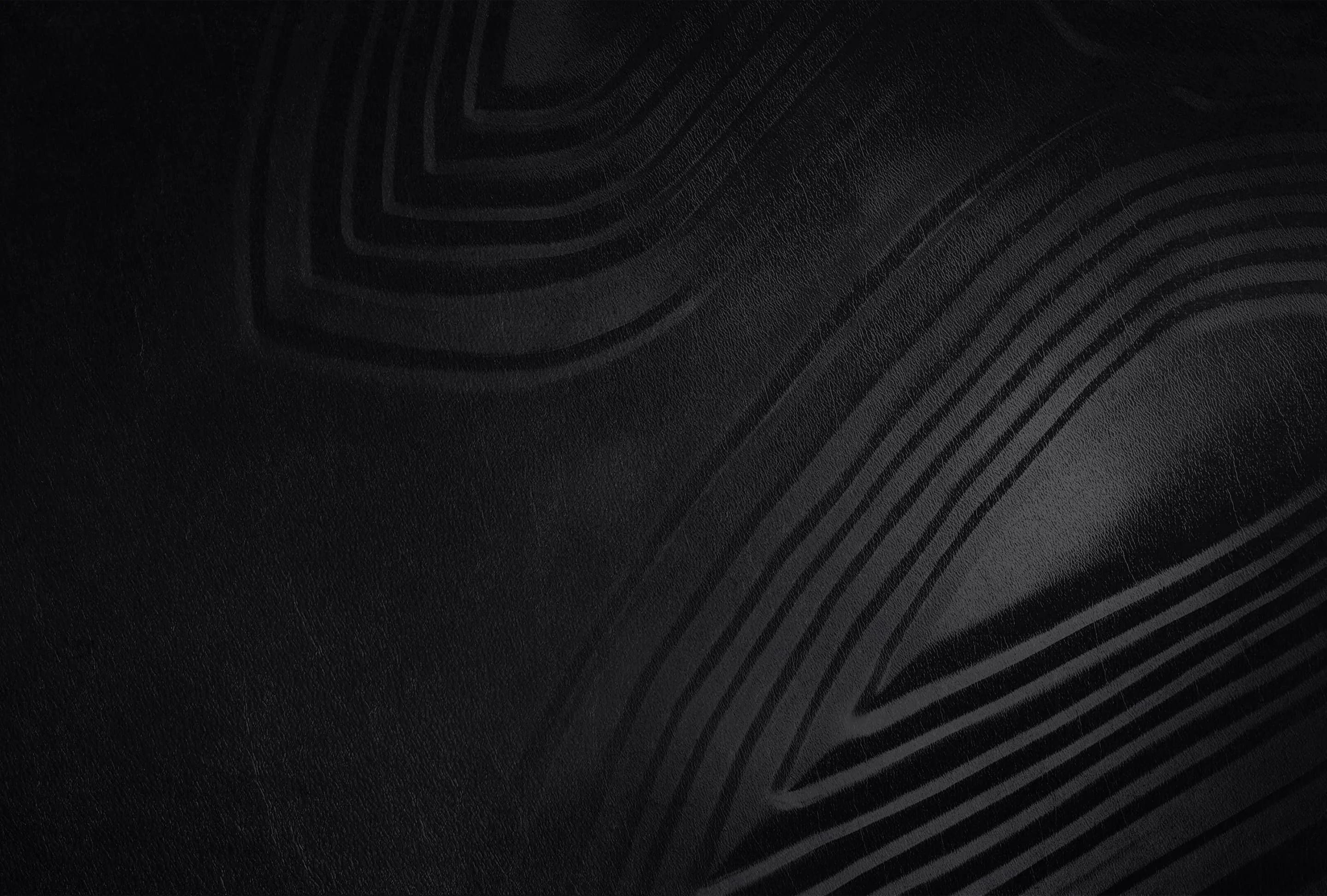 Concentric ridges press through a matte black surface like moulded rubber, lit from the upper left so only the raised edges catch light.