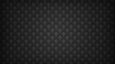 A tiny fan or scallop motif repeats in even rows across charcoal, lit from the centre so the edges of the frame fall away to black.