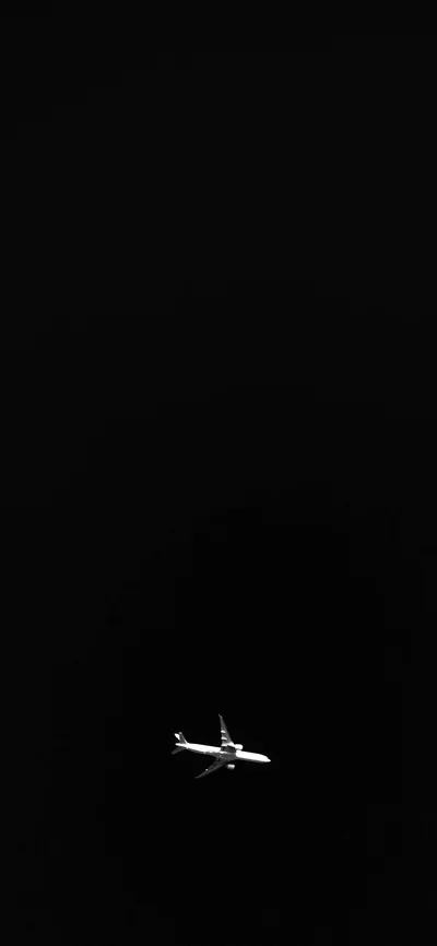 A small passenger jet catches a point of light in an otherwise empty black sky, sitting low in the frame with everything above it clear.