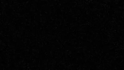 A flat black screen broken only by scattered specks of grey dust, dense enough near the top edge to notice and gone by the bottom.