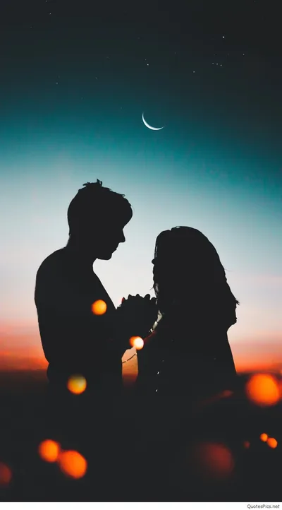 Two figures stand almost touching against a teal and orange dusk sky, a thin crescent moon above and orange bokeh below.