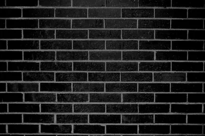 Even courses of black brick photographed flat, the mortar joints slightly paler and the surface roughest along the lower rows.