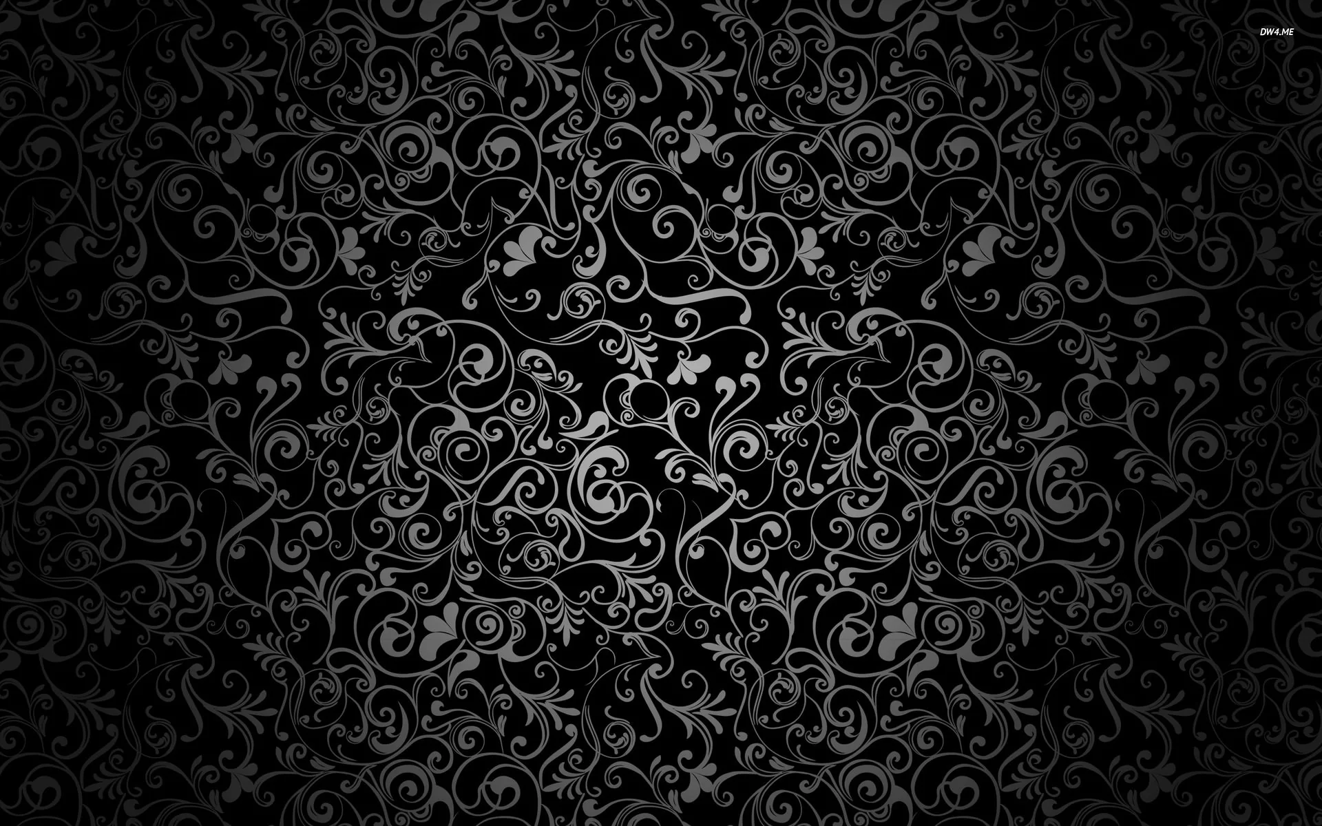 Curling vines and small blossoms radiate from the middle of the frame in dusty grey, the corners sinking into an almost solid black vignette.