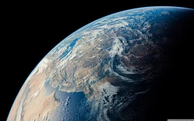 Desert plains and snow-dusted mountain ranges texture the sunlit surface filling the lower left, the black upper right corner left free for icons.