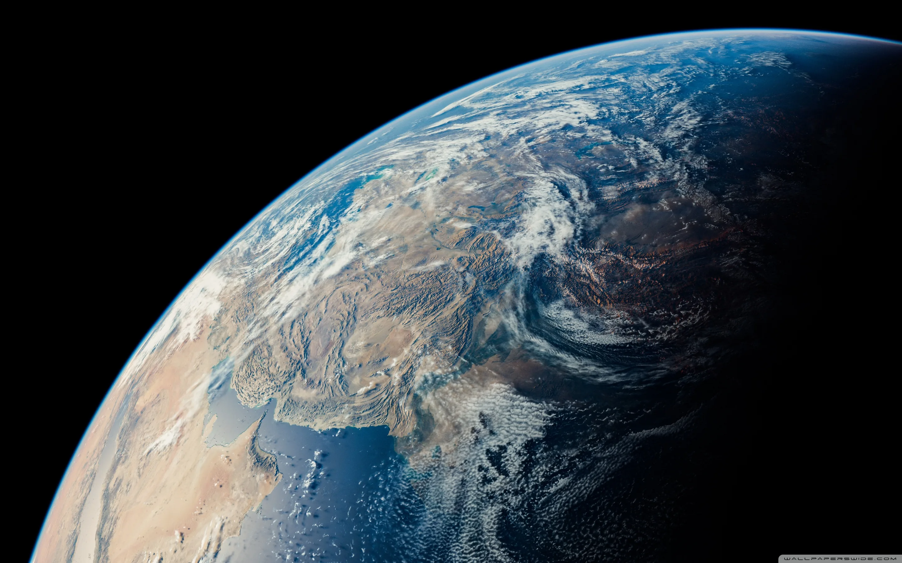 Desert plains and snow-dusted mountain ranges texture the sunlit surface filling the lower left, the black upper right corner left free for icons.