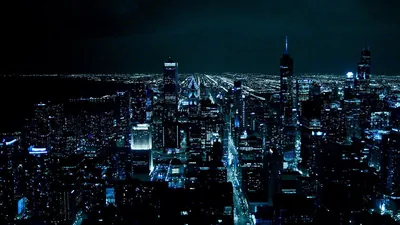 Downtown towers seen from a high vantage, streets running to the horizon as blue-white grids under a black sky.