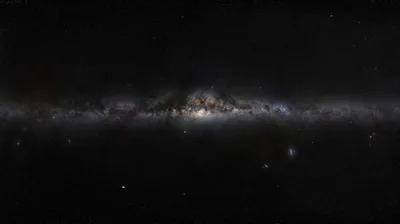 The galaxy's disc stretches horizontally through the middle of the frame, dust lanes silhouetted against a soft glow with black sky above and below.