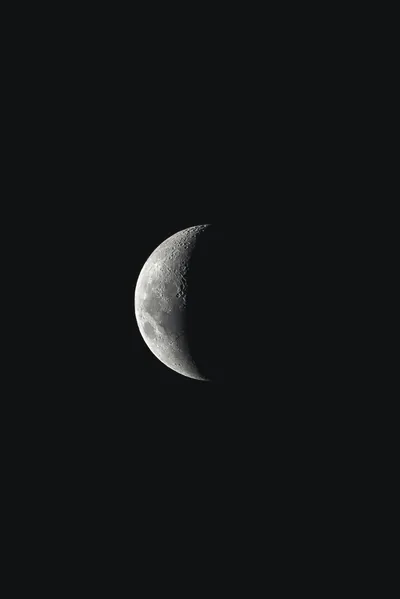 The moon sits slightly left of centre, lit from the right so the craters along the terminator stand out and the rest of the frame is empty black.