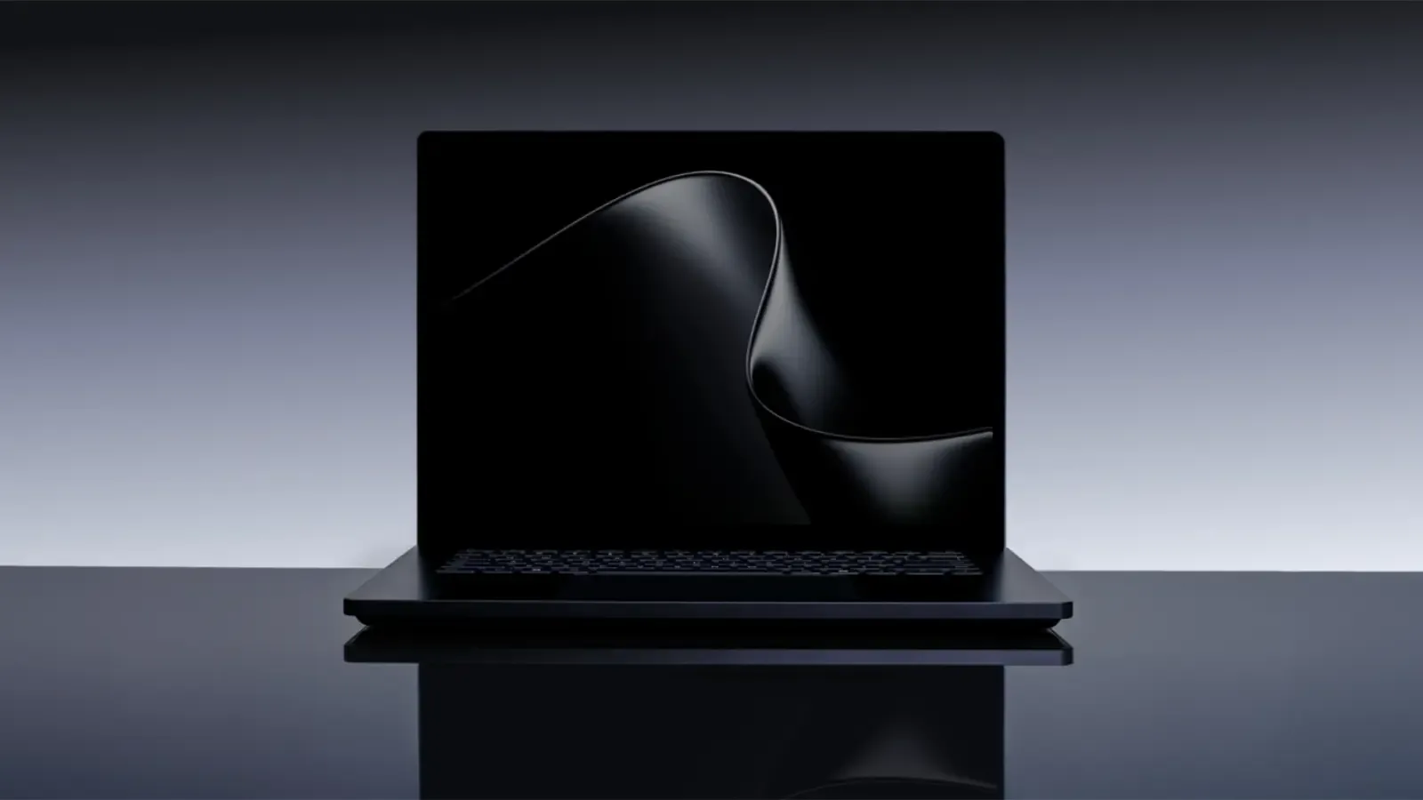 A slim black laptop sits open on a mirrored surface, a silky dark ribbon curling across its screen while the grey wall behind fades to black at the edges.