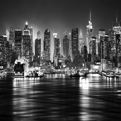 A wall of lit towers runs the full width of the frame, their reflections smeared into long streaks on the water below.