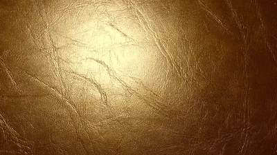 Creased metallic leather lit from the centre, fine wrinkles crossing the surface while the edges fall into a darker vignette.
