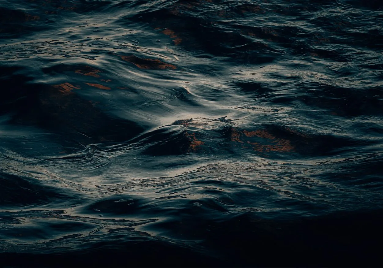 Low light skims across slow black-green swells, an almost abstract water texture that sits comfortably behind desktop icons.