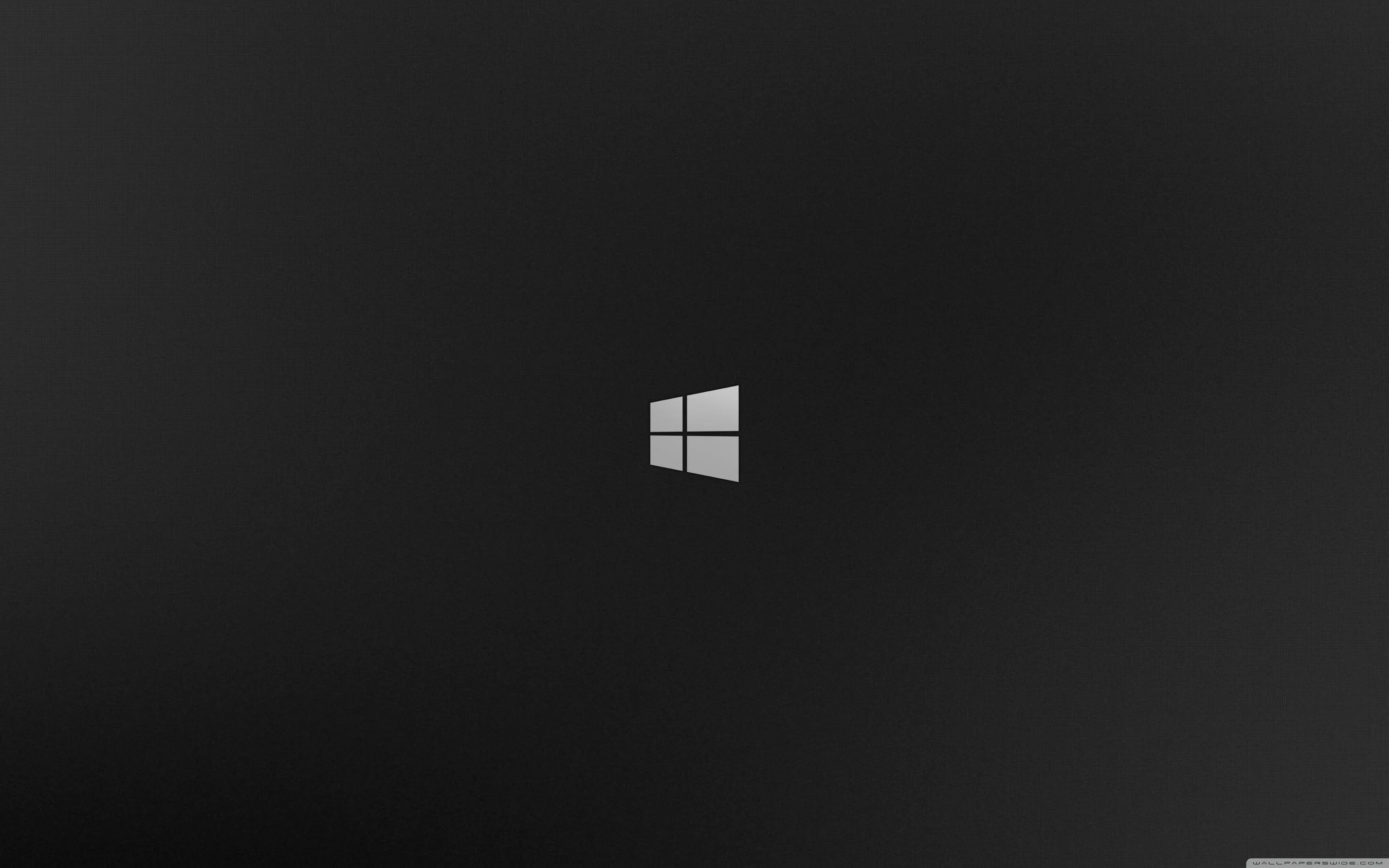 The four-pane Windows mark sits white and small at the centre of a grey-to-black gradient, the corners deep in shadow.