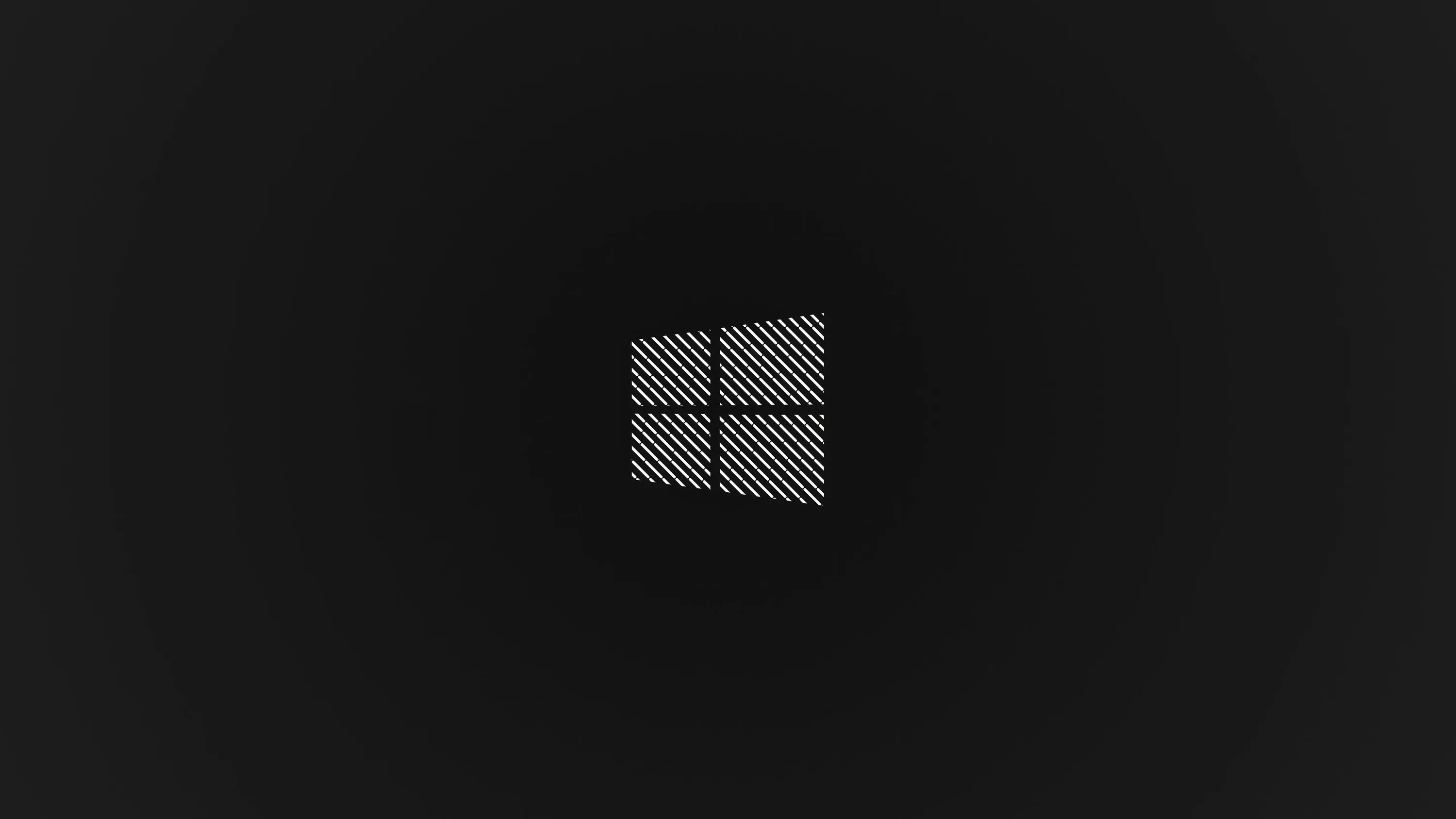 The Windows 10 square sits centred in a fine crosshatch texture on charcoal, the corners dropping to near black.