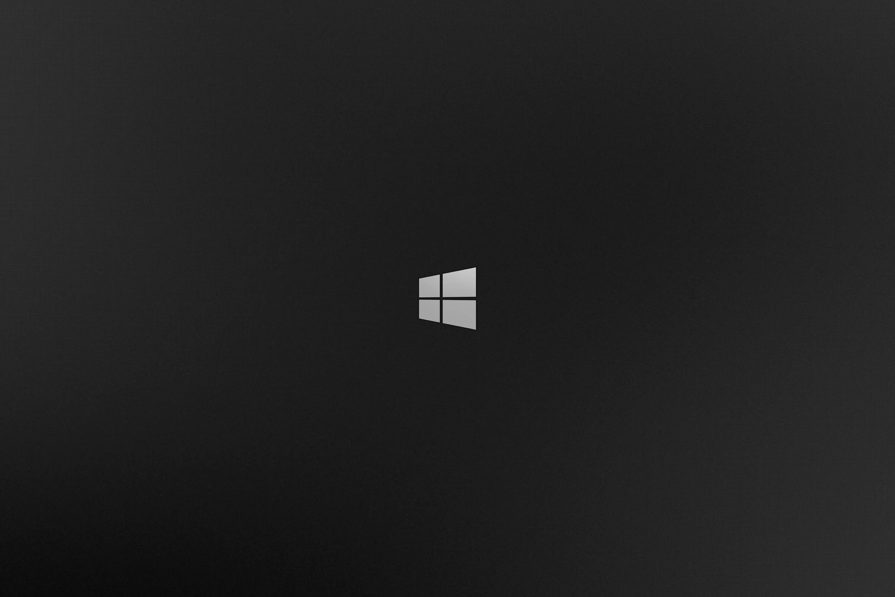 The white Windows 8 flag sits small and centred on a charcoal gradient that lightens slightly behind it, leaving the rest of the frame clear.