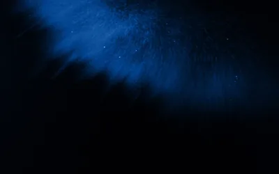 A soft cloud of blue dust drifts in from the upper right with a few bright specks in it, the lower half almost entirely black.