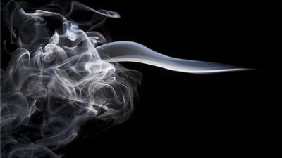 A plume unravels at the left while one glossy streak trails horizontally to the right edge, leaving the whole lower right corner clean black.