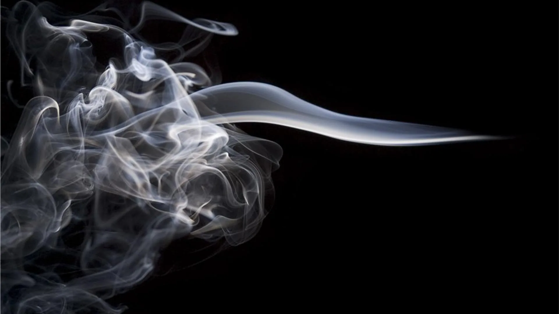 A plume unravels at the left while one glossy streak trails horizontally to the right edge, leaving the whole lower right corner clean black.