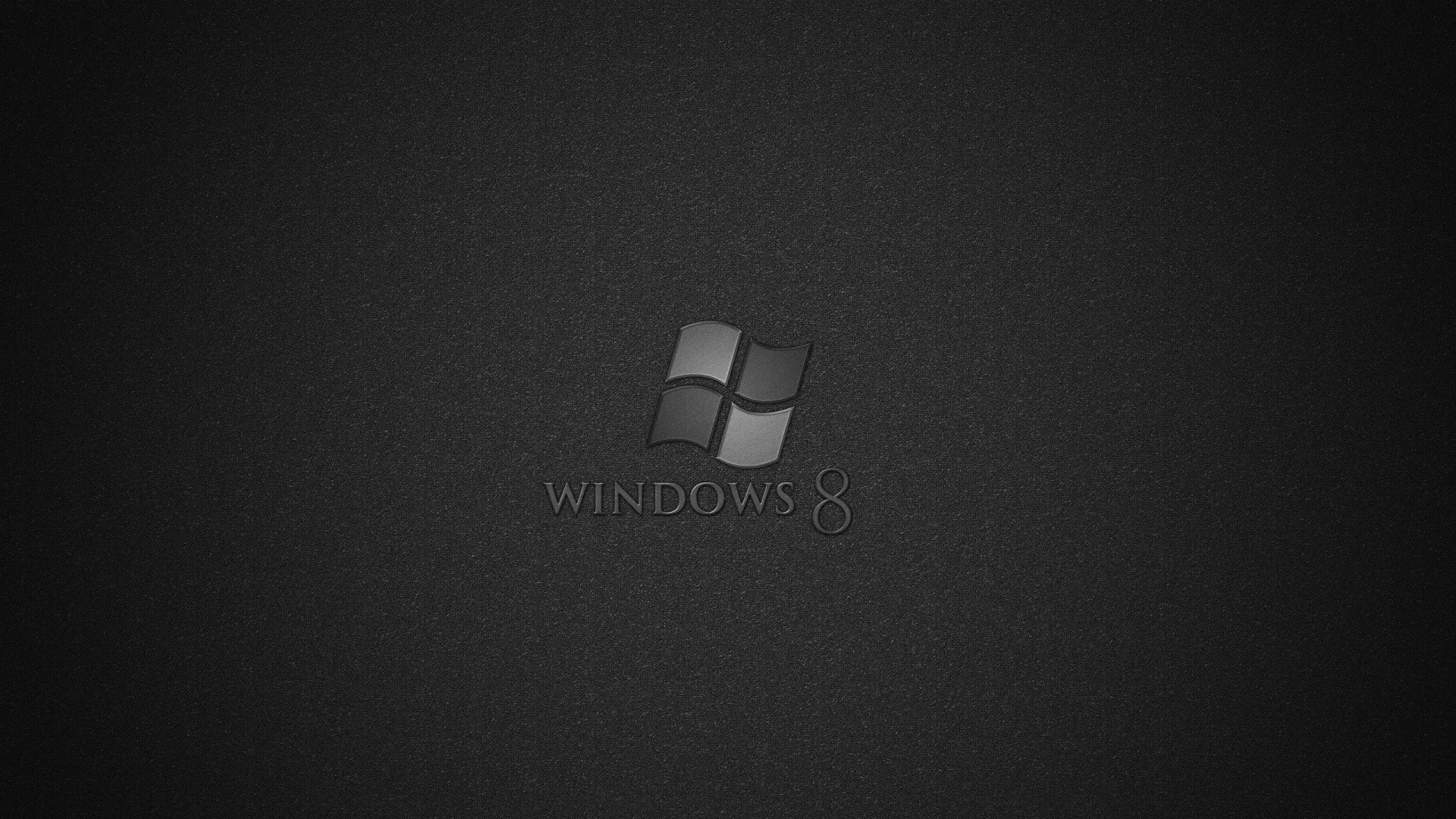 The four-pane Windows mark and its name sit embossed in grey at the centre of a grainy dark canvas, the corners pulled down by a heavy vignette.