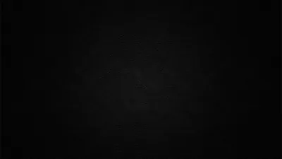 A flat dark wall with a barely-there grain, a hint of lift near the centre and full black at the edges.