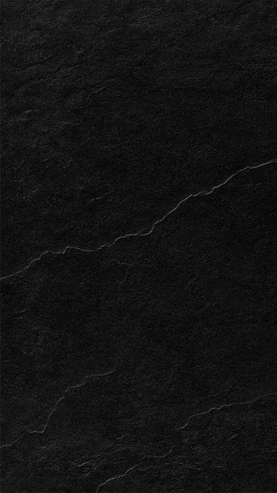 Rough slate fills the frame in deep black, thin pale cracks branching from the right edge across the middle while the base stays clean.