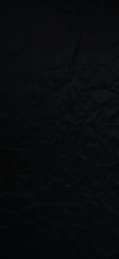 A sheet of black paper covers the tall frame edge to edge, its creases only visible where a weak light rakes across the upper half.