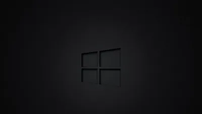 The Windows outline pressed into a near-black surface like a debossed stamp, visible only where a soft centre glow catches its edges.