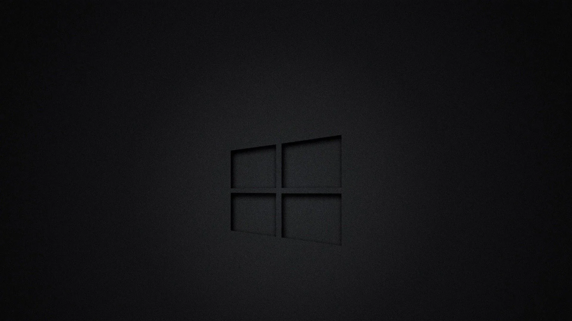The Windows outline pressed into a near-black surface like a debossed stamp, visible only where a soft centre glow catches its edges.