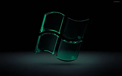 The waving four-pane emblem modelled in thick translucent green glass, its edges lit from behind and reflected on a dark grey floor.