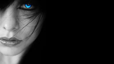 A woman's face fills the left edge, strands of hair across her cheek and a single desaturated blue eye, the right half of the frame left empty black.
