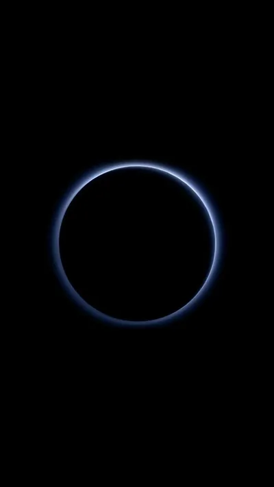 A planet lit from directly behind shows only a thin blue halo around its edge, the disc itself and everything around it left black.