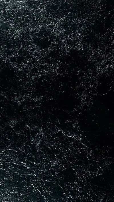 Pale veins fracture across polished black stone, brightest along the upper edge and fading into shadow lower down.
