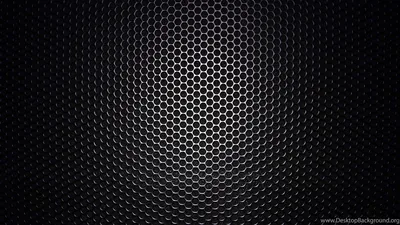 A wide field of small round holes in dark metal, lit from behind at the centre and falling away to black on both sides.