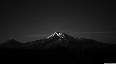 A ridge catches the last light on its snowy summit while the foothills and foreground sink into monochrome black.