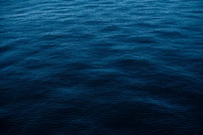 Gentle swells cross an empty stretch of prussian-blue ocean, evenly textured from edge to edge so a full grid of icons sits comfortably anywhere.
