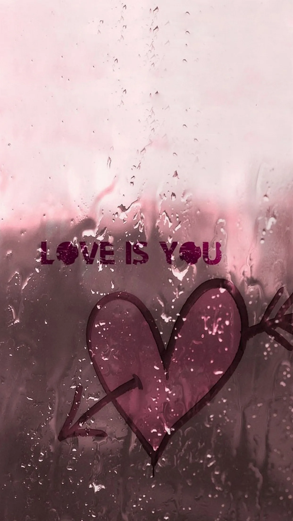 A finger-drawn heart pierced by an arrow and the words love is you sit on fogged glass, rain running down the pink pane.
