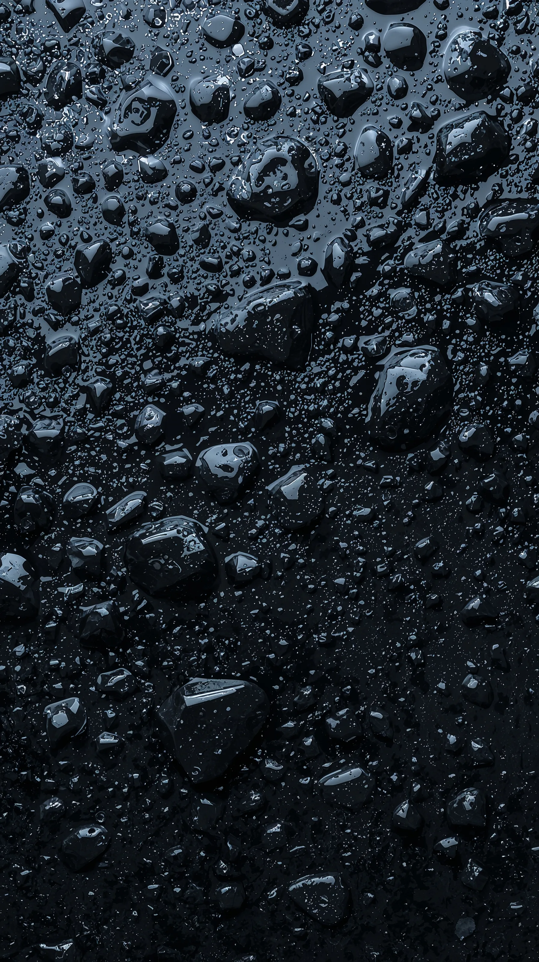 Beads of water sit across a slab of wet black stone, the largest drops clustered in the upper half and each holding its own highlight.