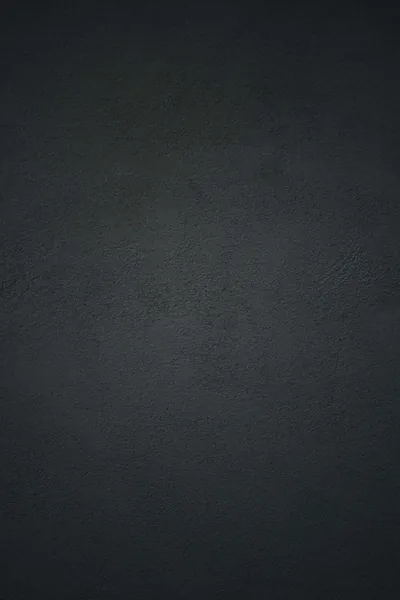 Pebbled charcoal leather fills the frame, the grain sharpest through the middle and softening into a dark vignette at the corners.