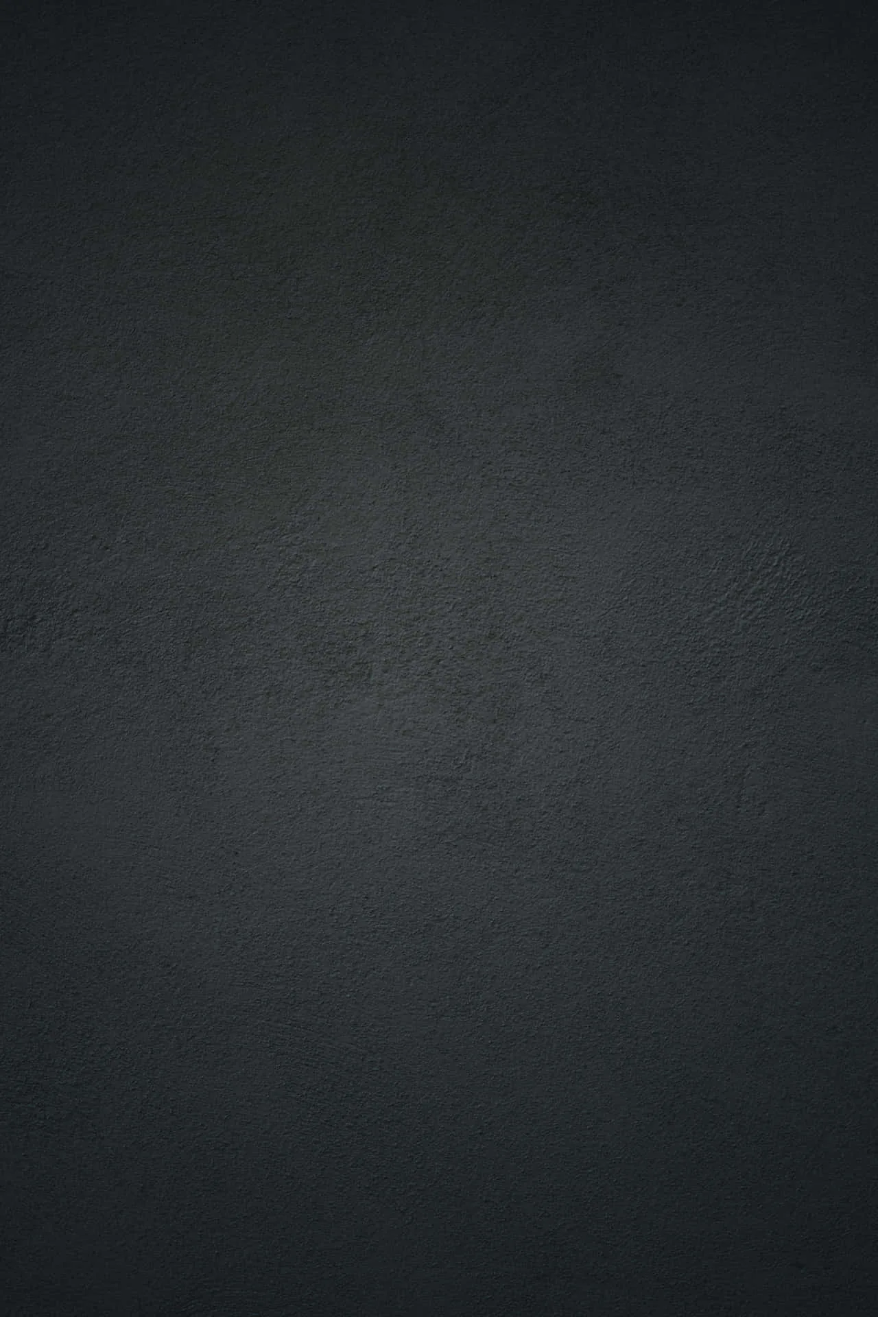 Pebbled charcoal leather fills the frame, the grain sharpest through the middle and softening into a dark vignette at the corners.